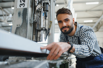 Jobs im Metallbau finden – junger Metallbauer arbeitet an einer Maschine
